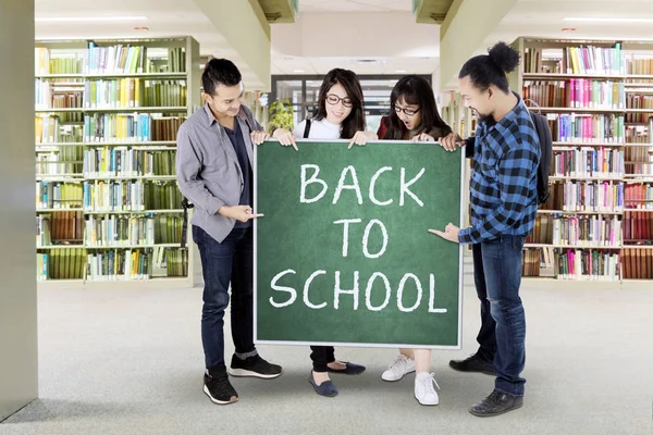 Os alunos guardam texto Back to School na biblioteca — Fotografia de Stock
