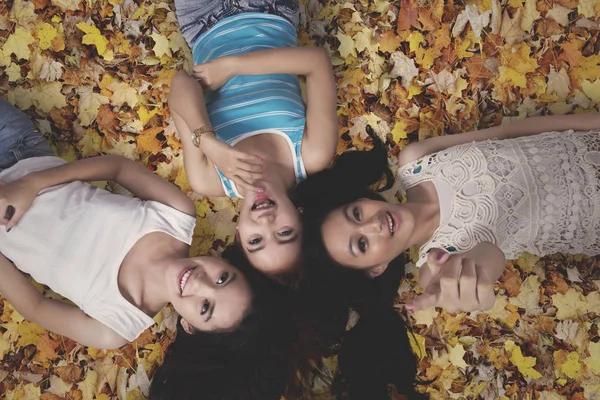 Três meninas deitadas nas folhas de outono — Fotografia de Stock