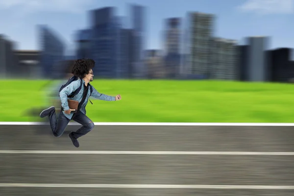 Estudiante universitario corriendo en la pista con libro — Foto de Stock