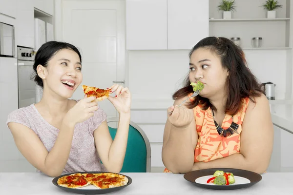 Mulher desfrutando de pizza e zombando de seu amigo — Fotografia de Stock