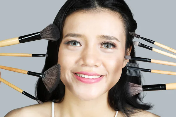 Ung kvinna med kosmetiska penslar — Stockfoto