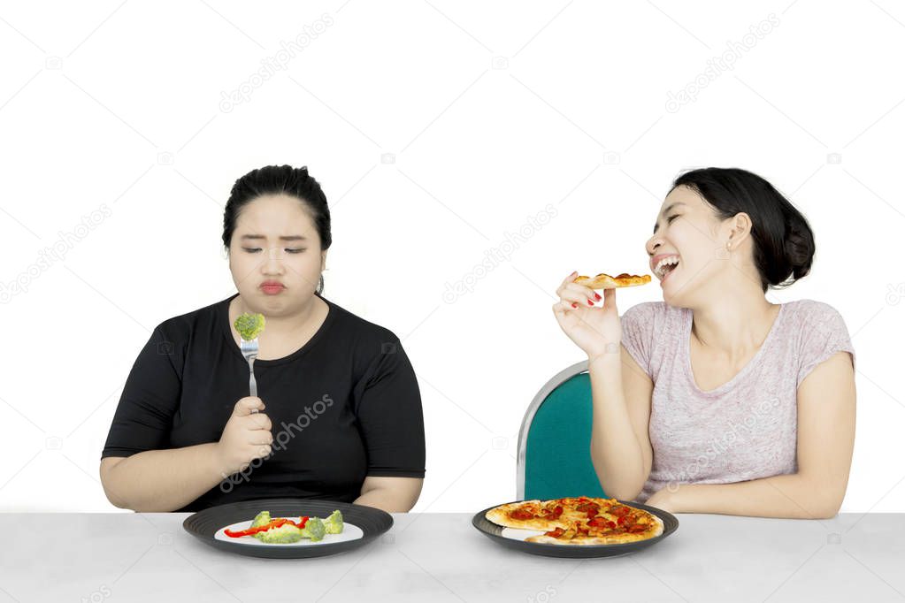 Obese woman eat salad and friend eat pizza