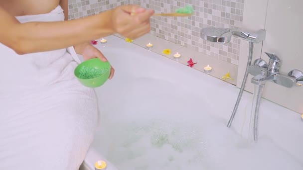 Tangan wanita menyebarkan garam spa di bak mandi — Stok Video