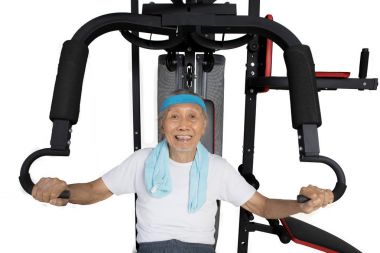 Yaşlı erkek ağırlık makine ile eğitiyor