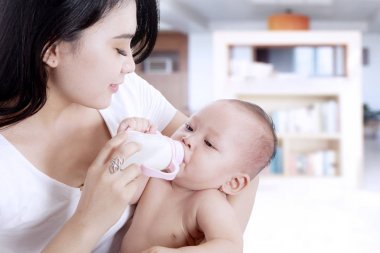 Bir şişe süt veren anne bebek