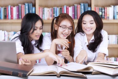 Üç öğrenci kitaplığındaki kitap okuma