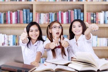 Üç öğrenci göster Tamam Kitaplığı'nda oturum