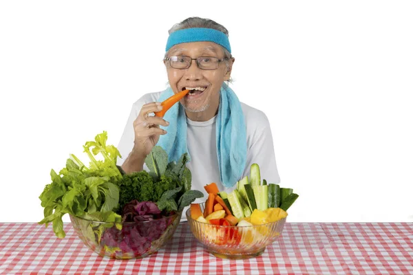 Viejo comiendo verduras orgánicas en el estudio — Foto de Stock