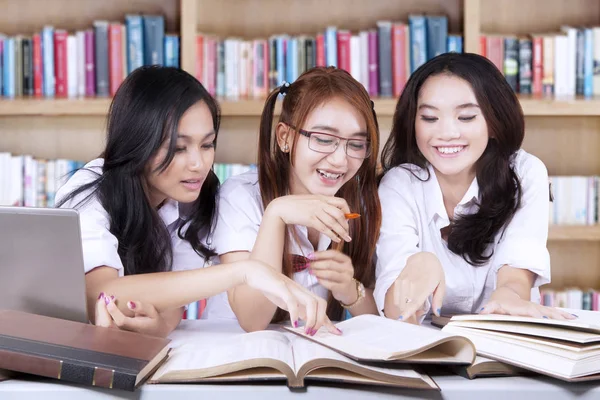 Üç öğrenci kitaplığındaki kitap okuma