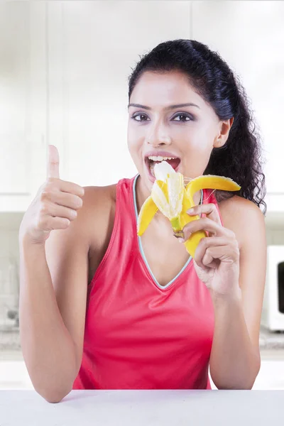 Mujer con plátano y el pulgar en la cocina —  Fotos de Stock