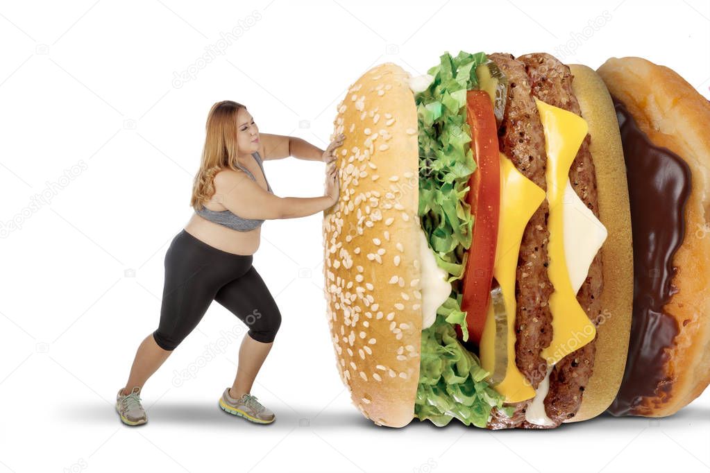 Mujer gorda empujando alimentos sabrosos en estudio Mujer gorda empujando alimentos sabrosos en estudio
