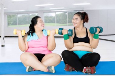 Mindere dumbbells ile iki şişman kadın