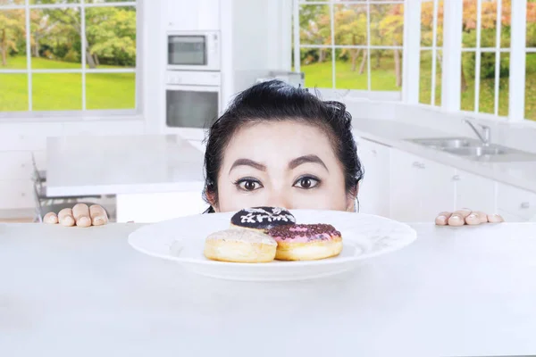 Mulher e donuts na cozinha — Fotografia de Stock