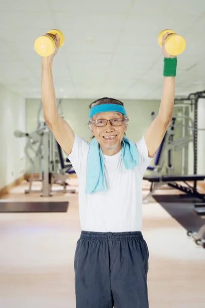 Staruszek, zniesienie dumbbells centrum fitness — Zdjęcie stockowe