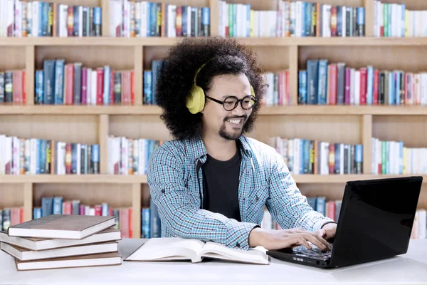 Samec studenta poslech hudby v knihovně — Stock fotografie