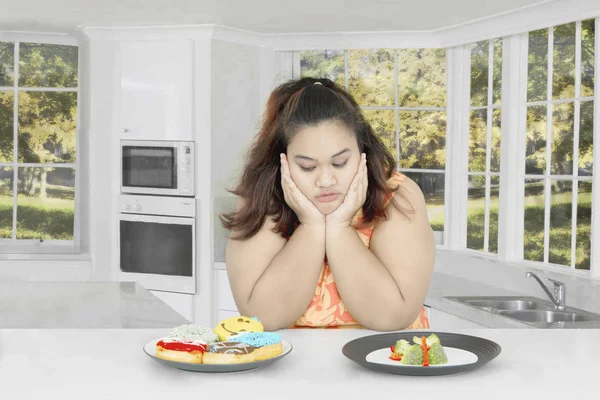 Товста жінка сумнівається в їжі — стокове фото