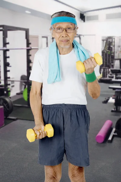 Hombre mayor con mancuernas en el gimnasio — Foto de Stock