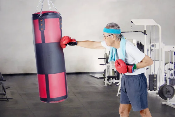 Idoso perfurando um saco de boxe — Fotografia de Stock