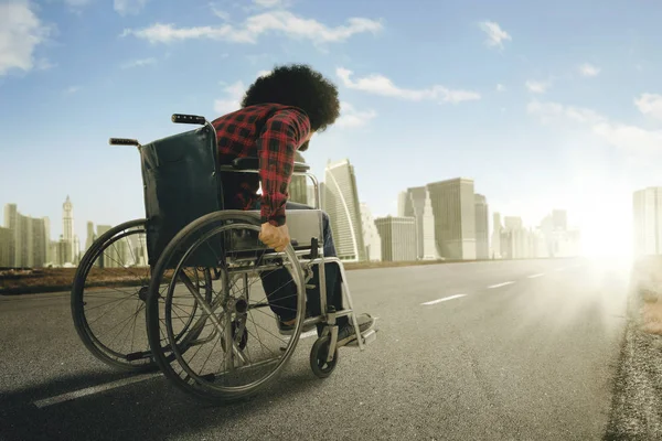 Afro-Mann läuft mit Rollstuhl auf der Autobahn — Stockfoto