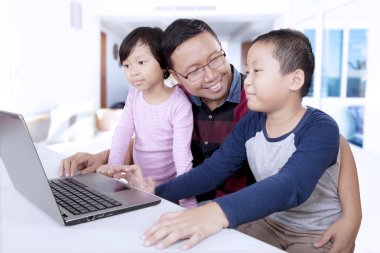Çocuklar babaları ile bir dizüstü bilgisayar kullanarak