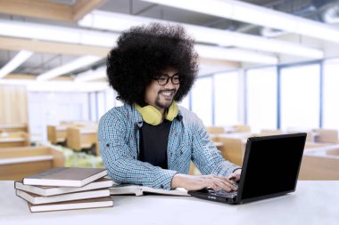 Bir dizüstü bilgisayar ve kitap ile Afro öğrenci