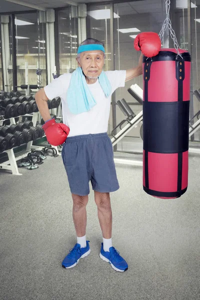 Old man leaning on boxing sack — Stock Photo, Image