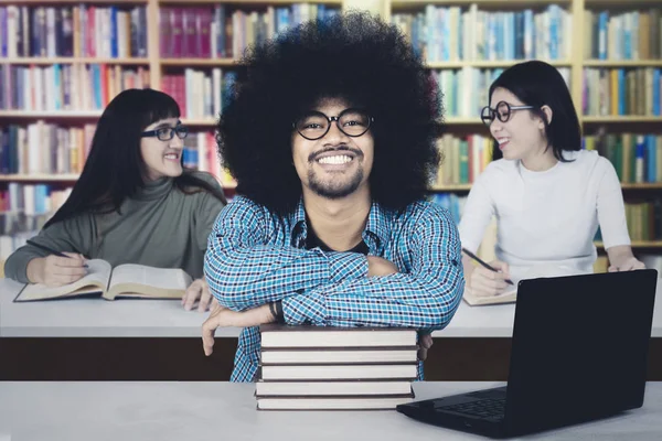 Estudante do sexo masculino com seus amigos na biblioteca — Fotografia de Stock