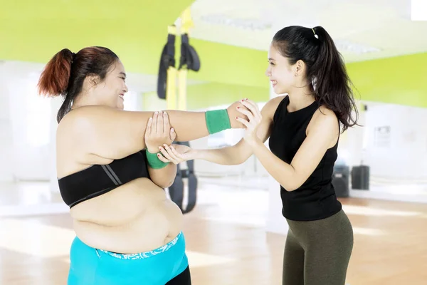 Instructora que ayuda a la mujer a hacer ejercicio — Foto de Stock