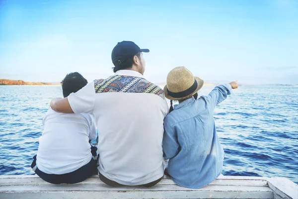 Vader met kinderen kijken naar de blauwe oceaan — Stockfoto