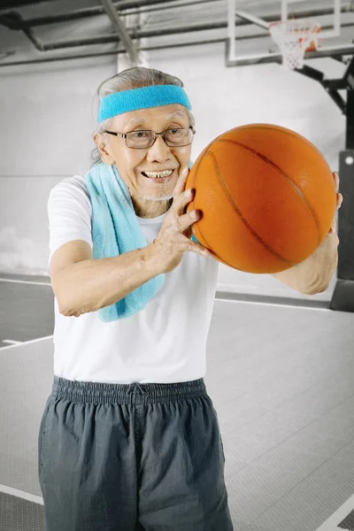 Elderly man playing a basketball in the stadium
