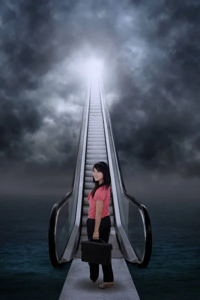 Empresária em pé na escada rolante para o céu — Fotografia de Stock