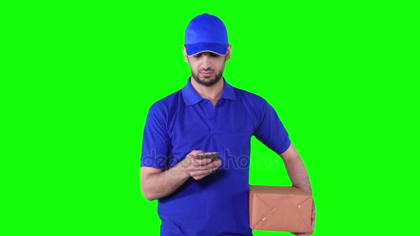 Доставка человек держит пакет и с помощью мобильного телефона — стоковое видео