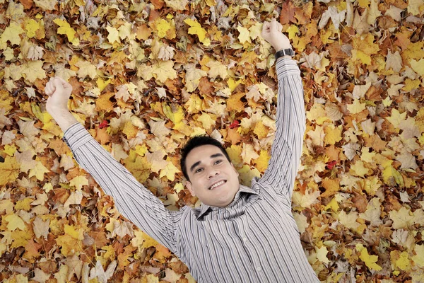 Young man lying down on the leaves autumn