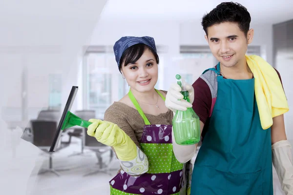 Pareja joven limpiando un espejo en la oficina —  Fotos de Stock