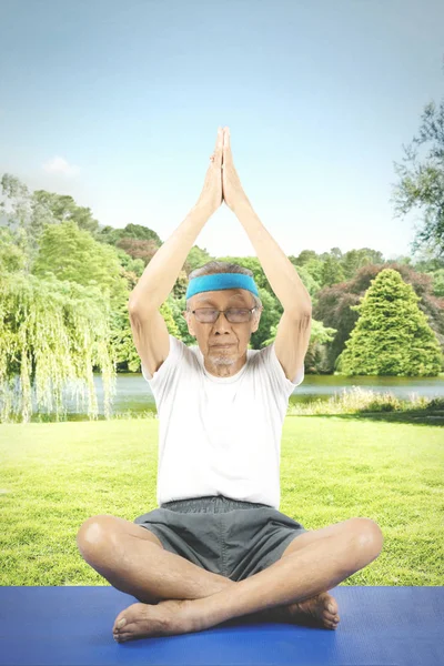 Elderly man practicing yoga in the park
