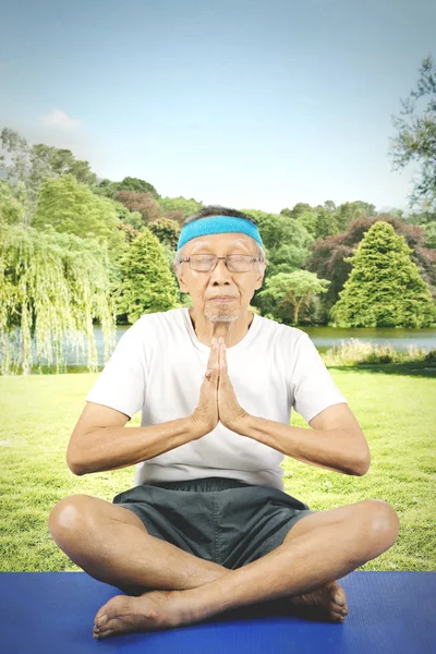 Elderly man doing yoga in the park
