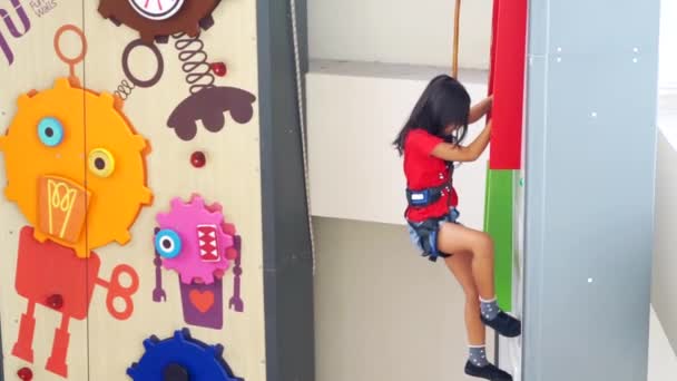 Little girl climbing a rock wall indoors — Stock Video