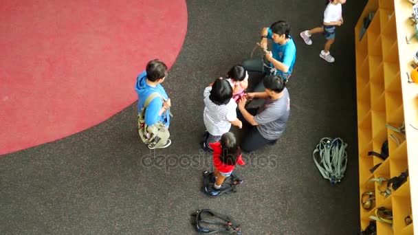 Instructor sets safety equipment to kids before climb — Stock Video