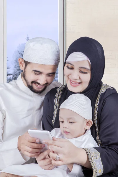 Мусульманская семья держит смартфон с зимой — стоковое фото