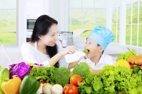 Kind probiert Salat mit seiner Mutter — Stockfoto