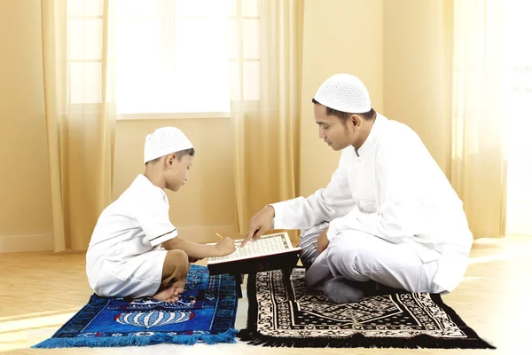 年轻的父亲给他的儿子教学古兰经 》 — 图库照片