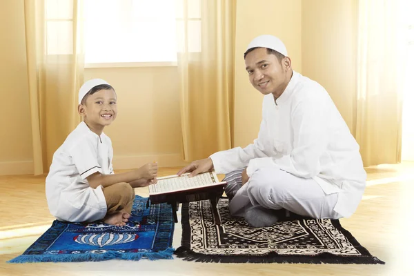 Pai e filho sorriem com o Alcorão em casa — Fotografia de Stock