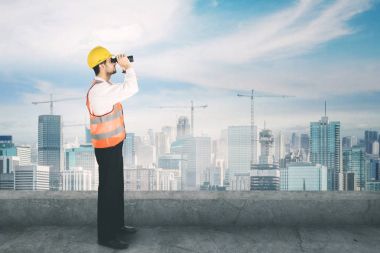 Çatı katında bir dürbün kullanarak genç mimar