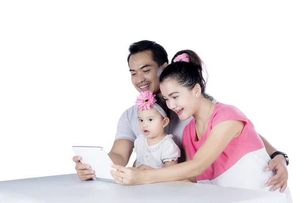 Padres jóvenes usando una tableta con su hija — Foto de Stock