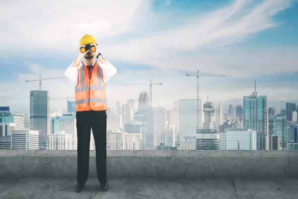 Jonge ingenieur met de verrekijker op het dak — Stockfoto