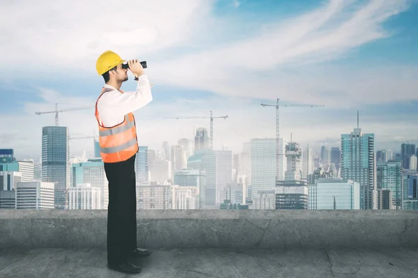 Joven arquitecto usando un binocular en la azotea — Foto de Stock