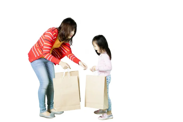 Mulher com criança segurando sacos de compras no estúdio — Fotografia de Stock