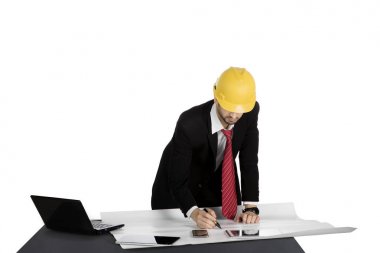 Erkek mimar planı ile masa üzerinde çalışmaktadır