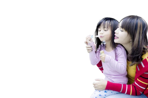 Mutter mit Tochter pustet Seifenblasen im Studio — Stockfoto