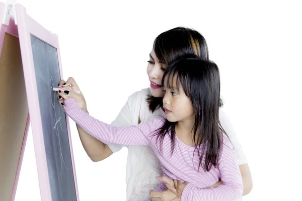 Маленька дівчинка з матір'ю малює крейдою — стокове фото
